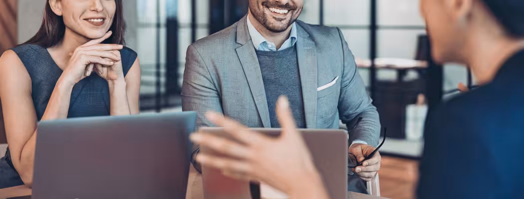 Réunion professionnelle avec plusieurs personnes souriantes discutant autour d’un ordinateur, illustrant l’écoute et la compréhension client chez Keiyo