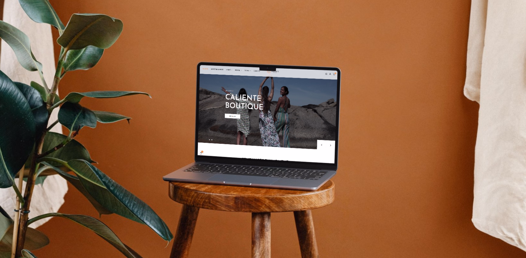 Site e-commerce de Boutique Caliente affiché sur un MacBook posé sur un tabouret en bois